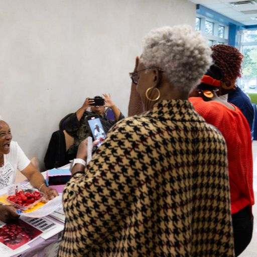 A Black woman with gray hair and a checked shawl meets with other women at the Women’s Health, Motivation, and Empowerment Conference at ACC.